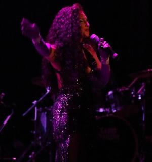 一位女士在舞台上对着麦克风唱歌