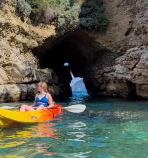 a woman in a kayak in front of a cave