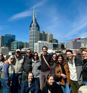 skupina lidí pózujících pro fotografii před městem