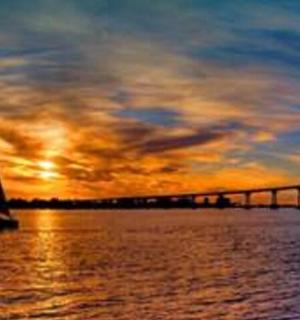 a sail boat in the water near a bridge