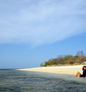 一位女士坐在沙滩上的水中