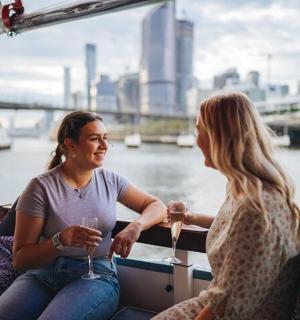 two people sitting on a boat with wine glasses
