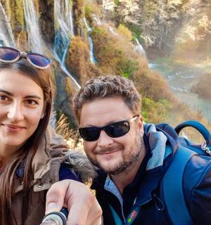 a man and a woman standing in front of a rainbow