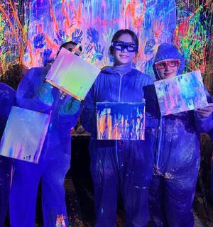 skupina lidí držících obrazy před zdí