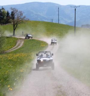 a group of cars driving down a dirt road
