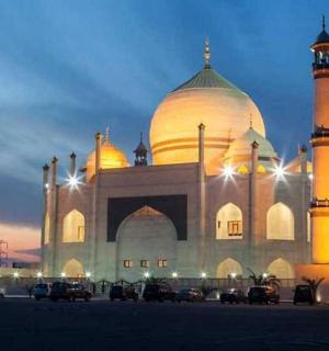 a large building with a domed building with cars parked in front