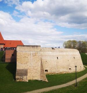 a large brick building with a red roof on a field