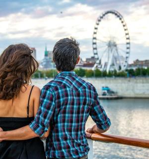 a man and a woman standing on a fence looking at a ferris wheel