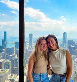 two women posing for a picture at the top of a skyscraper