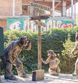three statues of people standing next to a street sign