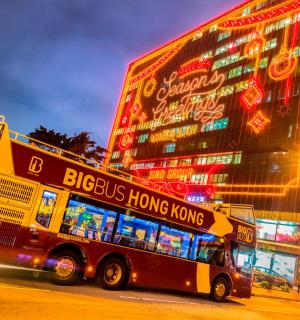 dvoupatrový autobus projíždějící kolem velké budovy