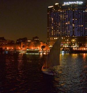一艘帆船在水中，城市夜景