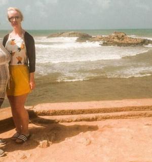 two women standing on a wall near the ocean