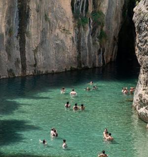 一群人在洞穴附近的河里游泳