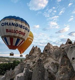 two hot air balloons flying over a rocky mountain