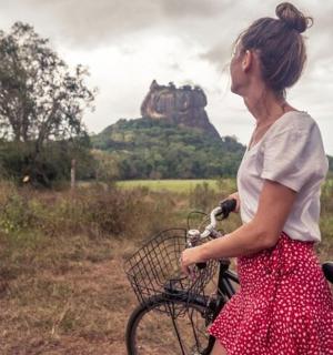a woman riding a bike with a castle in the background