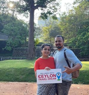a man and woman holding a sign in a park