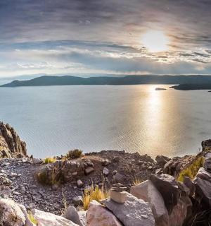 muž stojící na vrcholu hory s výhledem na vodní plochu