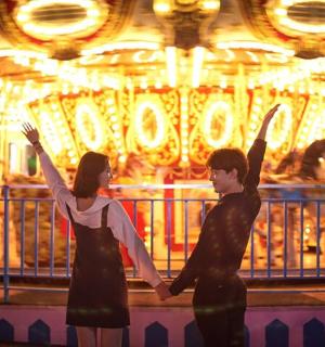 a man and a woman standing in front of a carousel