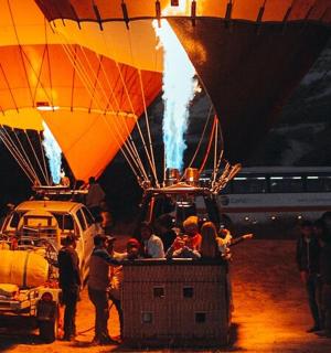 a group of people standing next to two hot air balloons