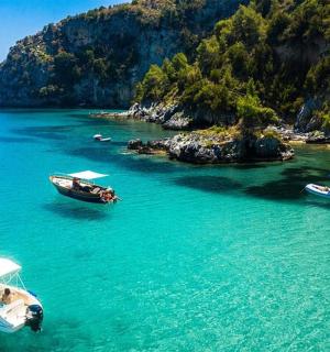 tři lodě ve vodě poblíž malého ostrova