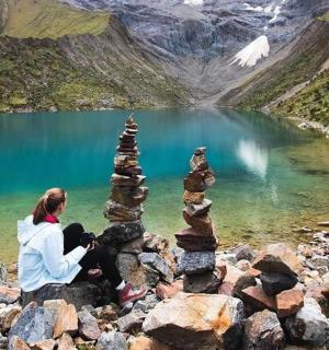 žena sedící na hromadě kamenů u jezera