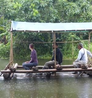 a group of people sitting on a bamboo raft in the water