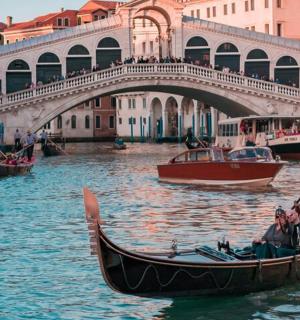a man in a gondola on the water near a bridge