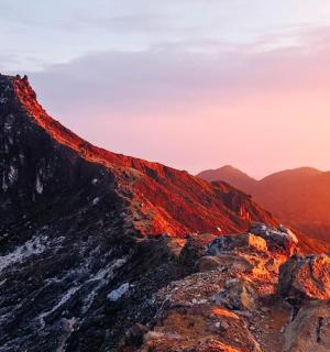 a view of a mountain with the sun setting on it