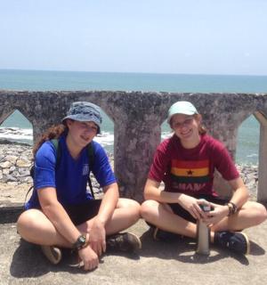 两个女孩坐在海边的墙上