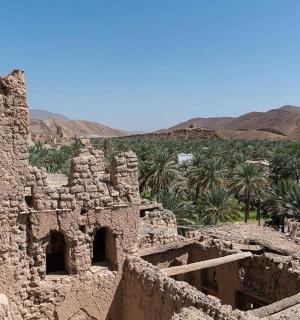 an old stone building with trees and mountains in the background