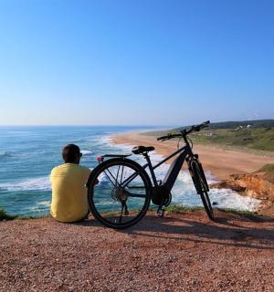 一名男子坐在沙滩上的一辆自行车旁边