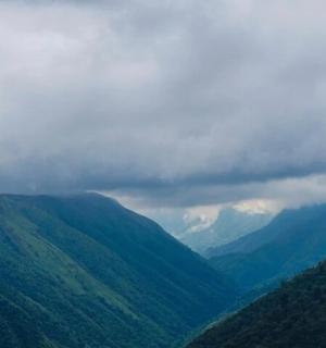 a view of a mountain valley with clouds in the sky