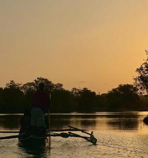 muž v lodi na řece při západu slunce