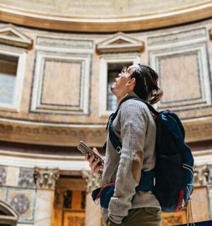 一名背着背包的女子正在拍摄一栋建筑