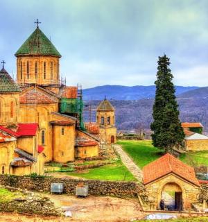 an old church on a hill with mountains in the background