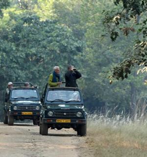 dva muži stojící na zadních částech dvou nákladních aut na prašné cestě