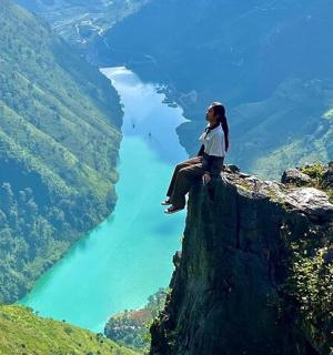 一位女士坐在悬崖边上，俯瞰着一条河流