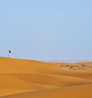 一名男子站在沙漠沙丘顶上