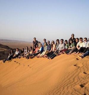 skupina lidí sedících na vrcholu písečné duny