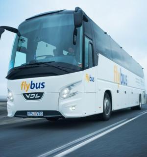 a white bus driving down a road