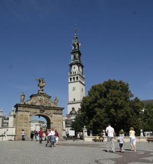 skupina lidí jdoucích před budovou s věží