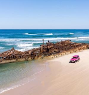 a pink car parked on a beach near the ocean
