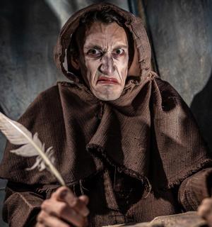 un vell que sosté una ploma a la mà