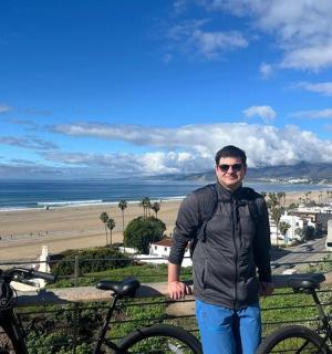 a man standing next to two bikes in front of the beach