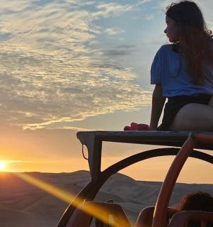 一位女士坐在长椅上看日落