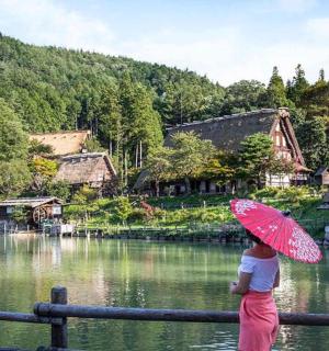 žena držící růžový deštník poblíž řeky