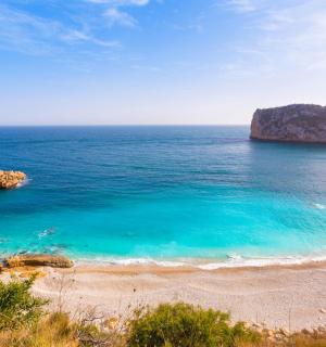a view of a beach with blue water and rocks