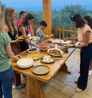eine Gruppe von Menschen steht mit Essen um einen Tisch herum