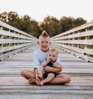 chlapec a dítě sedící na mostě